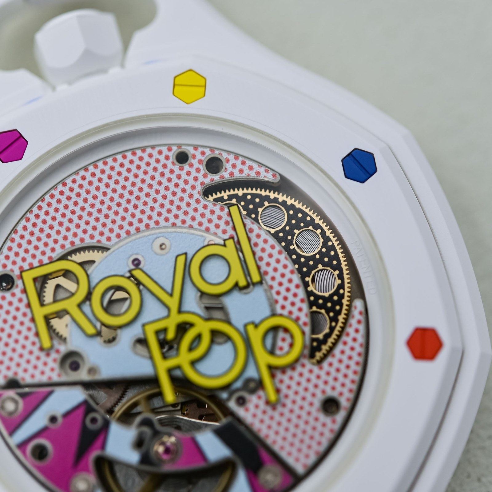Huit Blanc caseback close-up showing the randomly-assembled colored hexagonal bezel screws and the Royal Pop pop-art SISTEM51 movement visible through sapphire