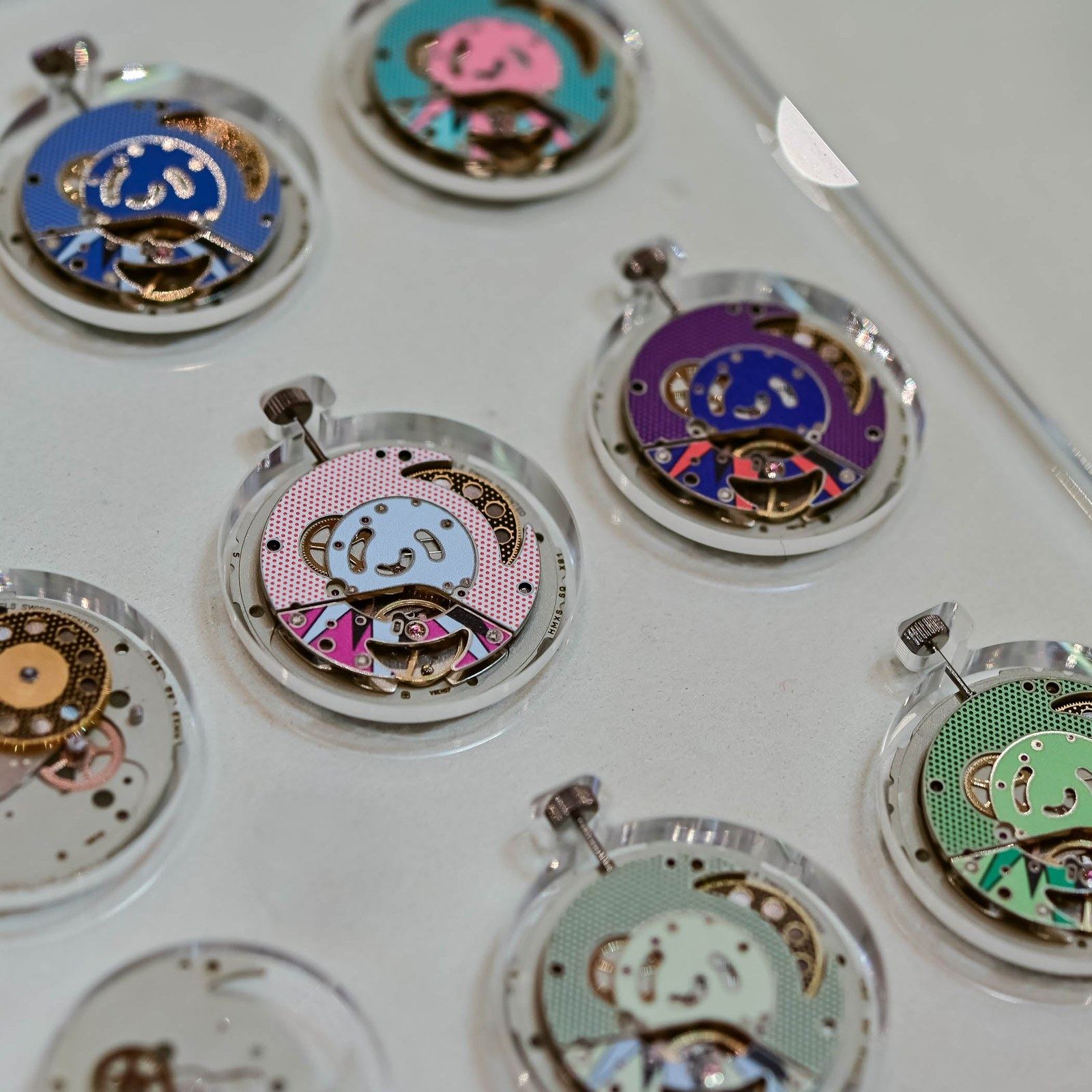 Eight Royal Pop SISTEM51 hand-wound movements on a workshop tray, each finished in pop-art colors mirroring its watch case