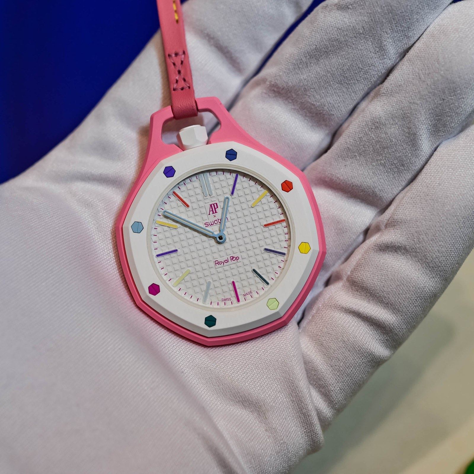 The eight Audemars Piguet × Swatch Royal Pop pocket watches arranged with their colored leather lanyards on a cream paper backdrop