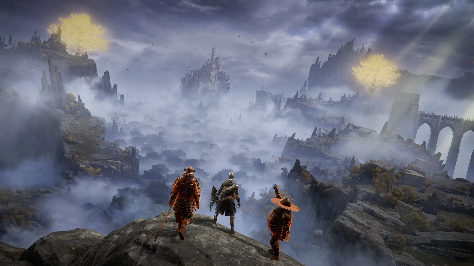 Three players standing together on a cliff edge looking out over misty ruins