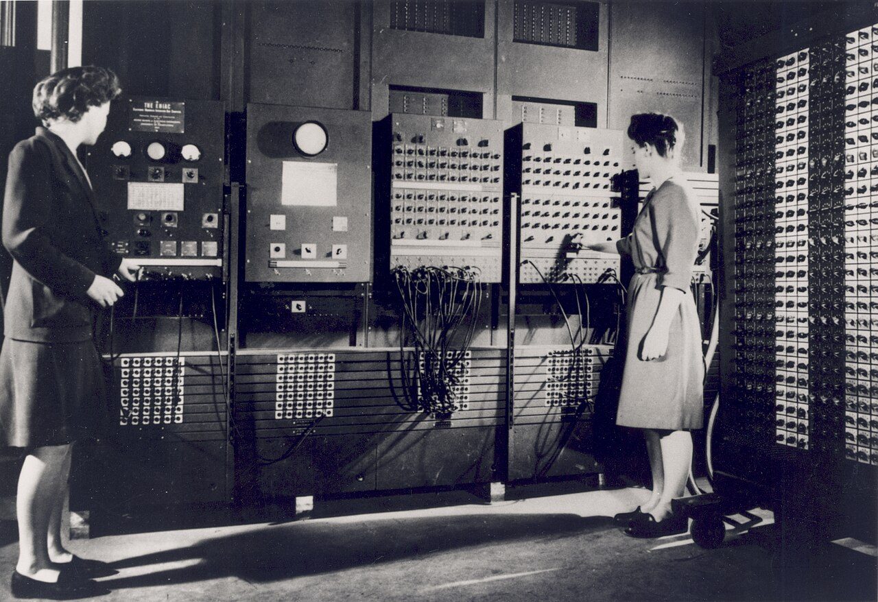 Two women setting up ENIAC, among its panels and cables