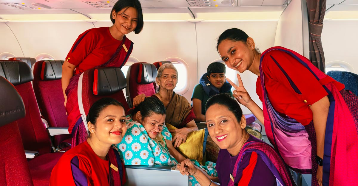 Beeja in her seat on the plane in the same flowered nightdress, her elderly mother beside her in a sari, surrounded by four smiling cabin crew in red uniforms, one making a peace sign