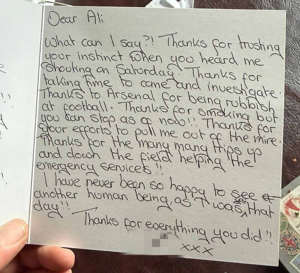 A handwritten thank-you card on white paper, held in someone's hand, beginning Dear Ali and signed off with three kisses, the signature blurred out