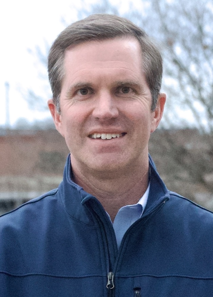 A close portrait of Governor Andy Beshear outdoors, smiling