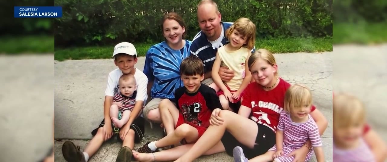 A family snapshot on a garden path: a mother and father sitting with six young children around them, the youngest a baby on a boy's lap.