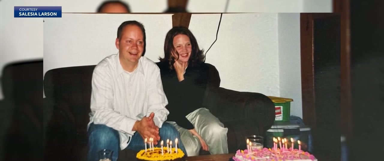 An old snapshot of a young man in a white shirt and a young woman with dark hair sitting on a sofa behind two birthday cakes lit with candles.