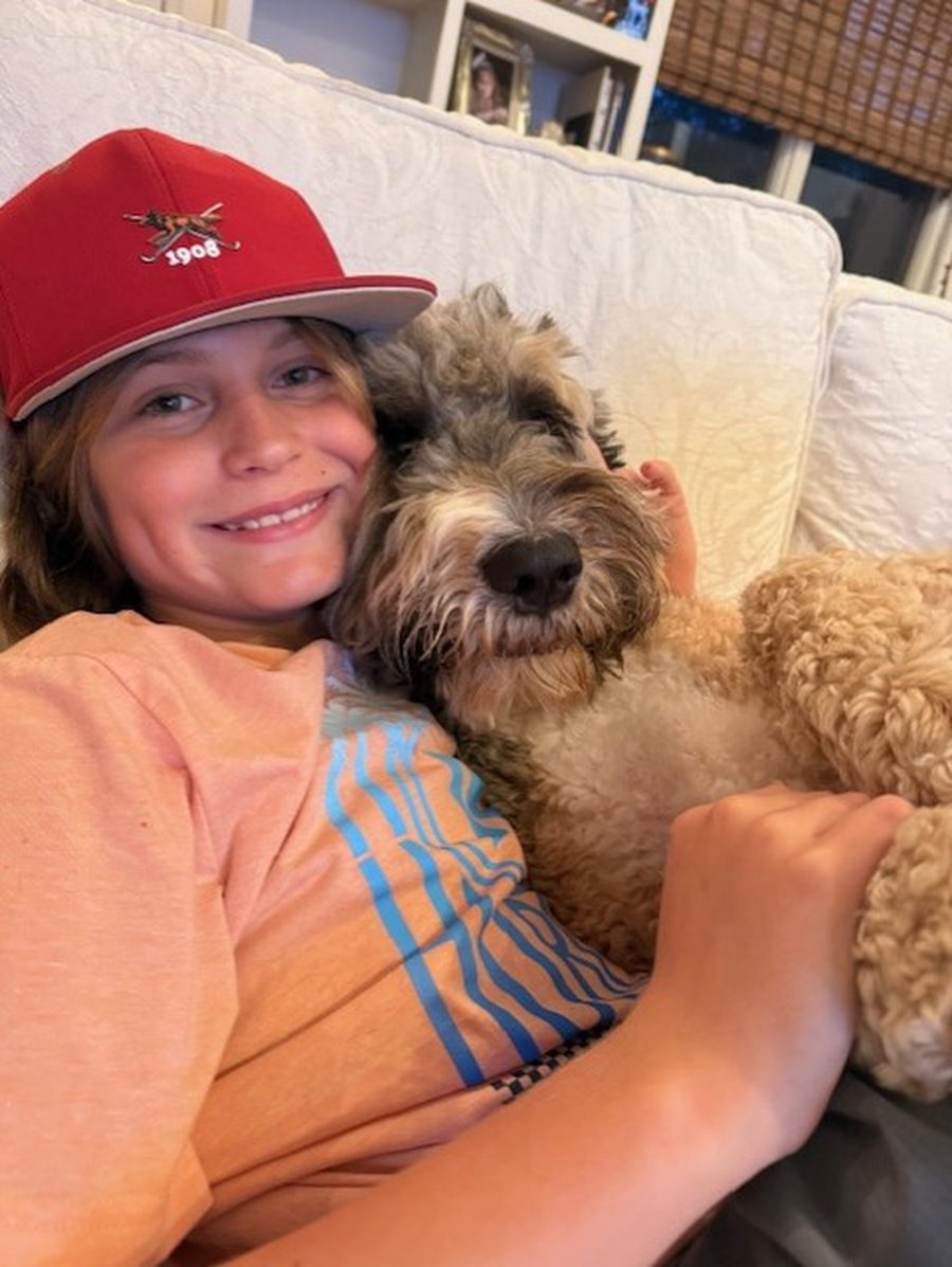 Major Metzger at home in a red cap with his arm around a shaggy dog