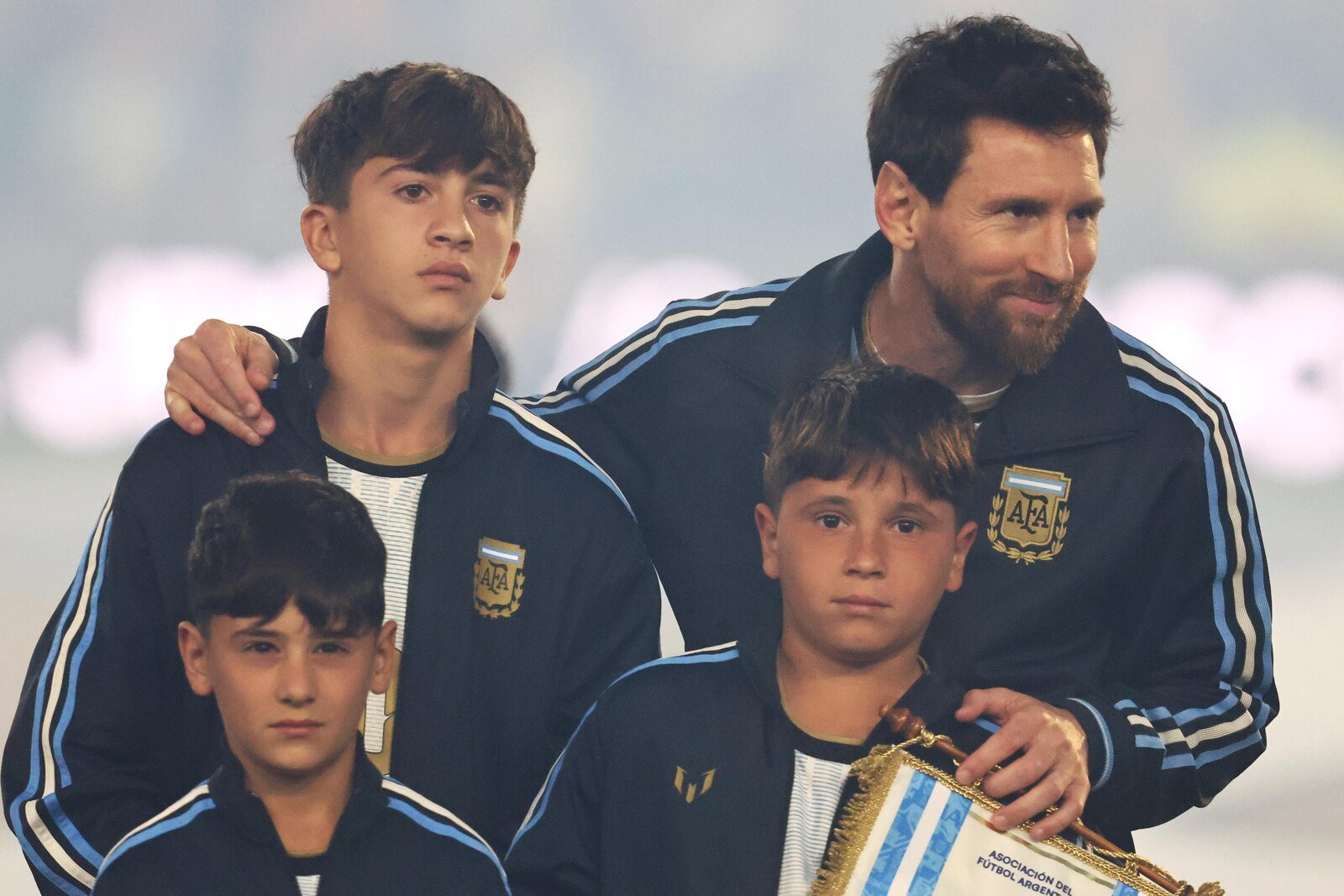 Lionel Messi in an Argentina tracksuit with his arm around one of his sons, his other two sons in front of him, before the match.