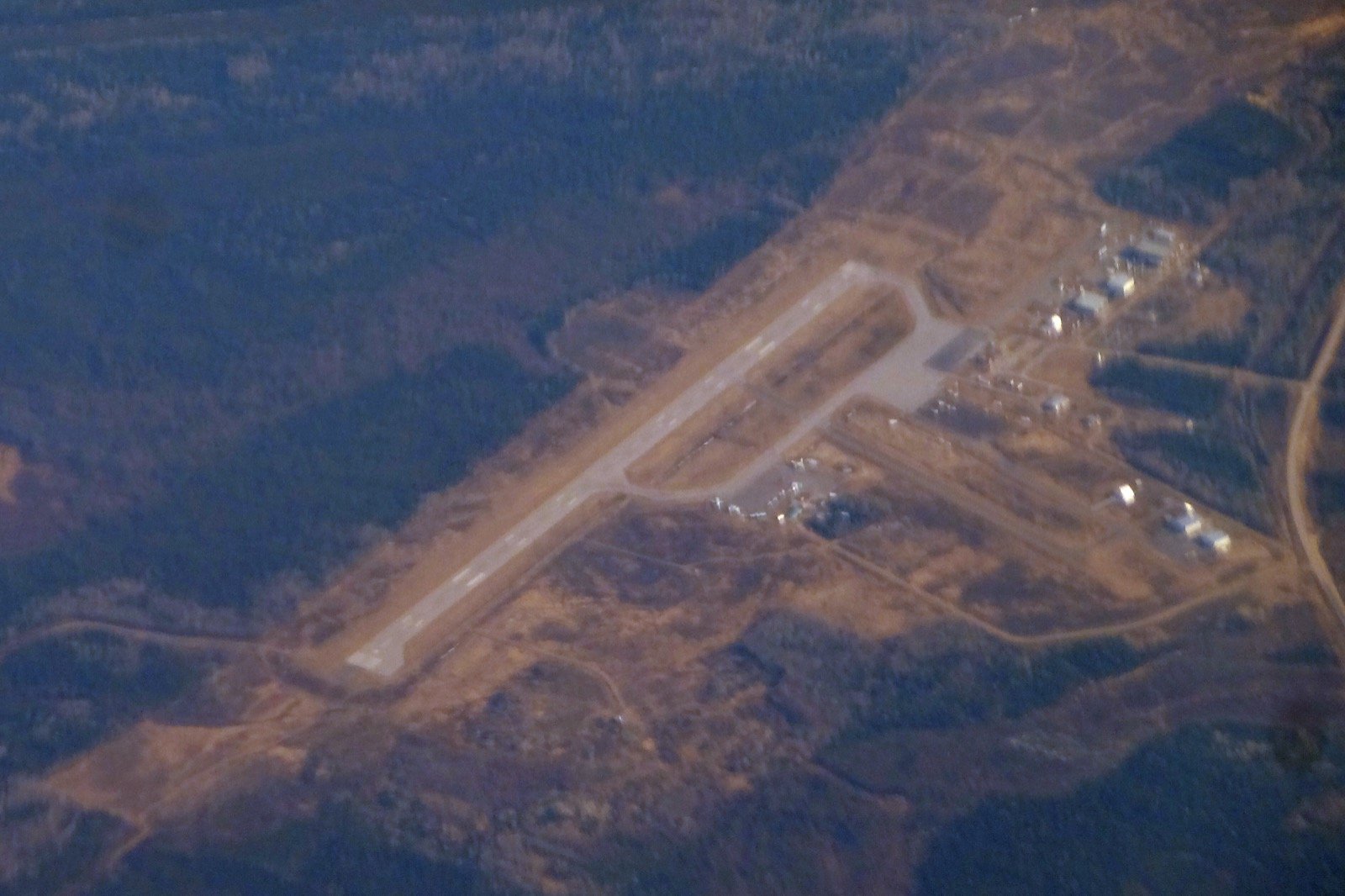 The airstrip at La Ronge seen from high above, a cleared strip in the forest, lake and hills beyond