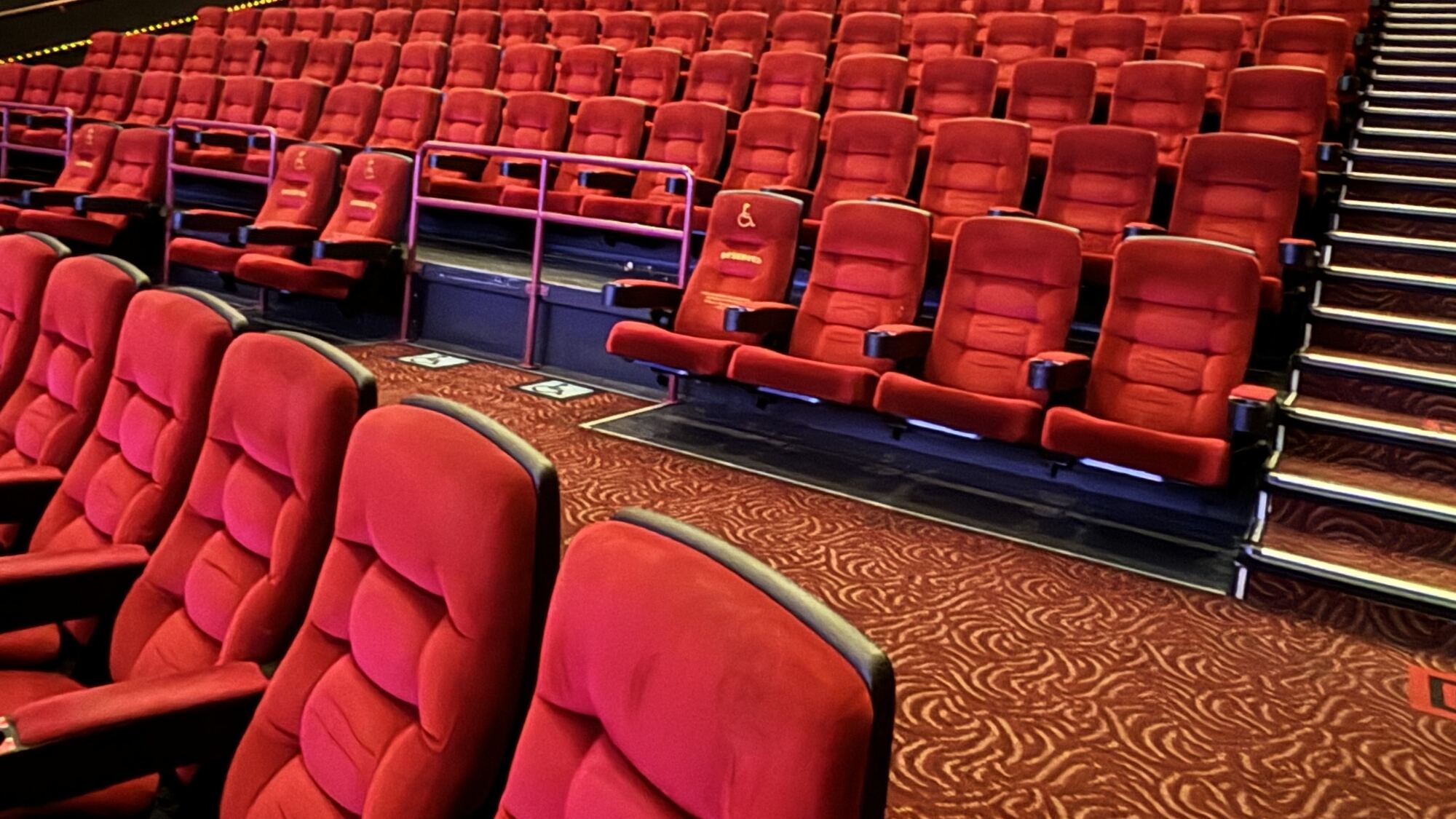 Rows of empty red cinema seats under ceiling lights