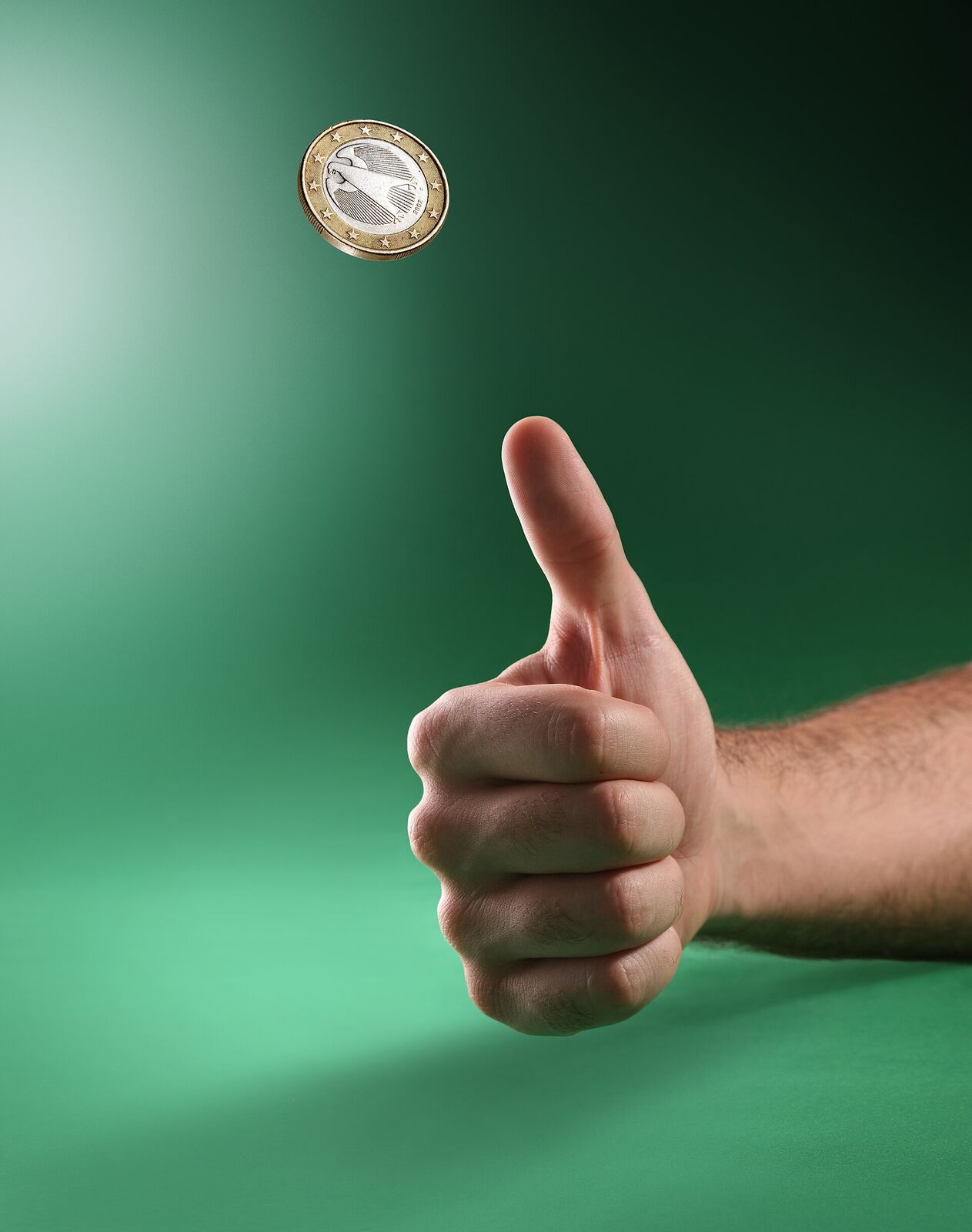 A coin spinning in the air above a thumb