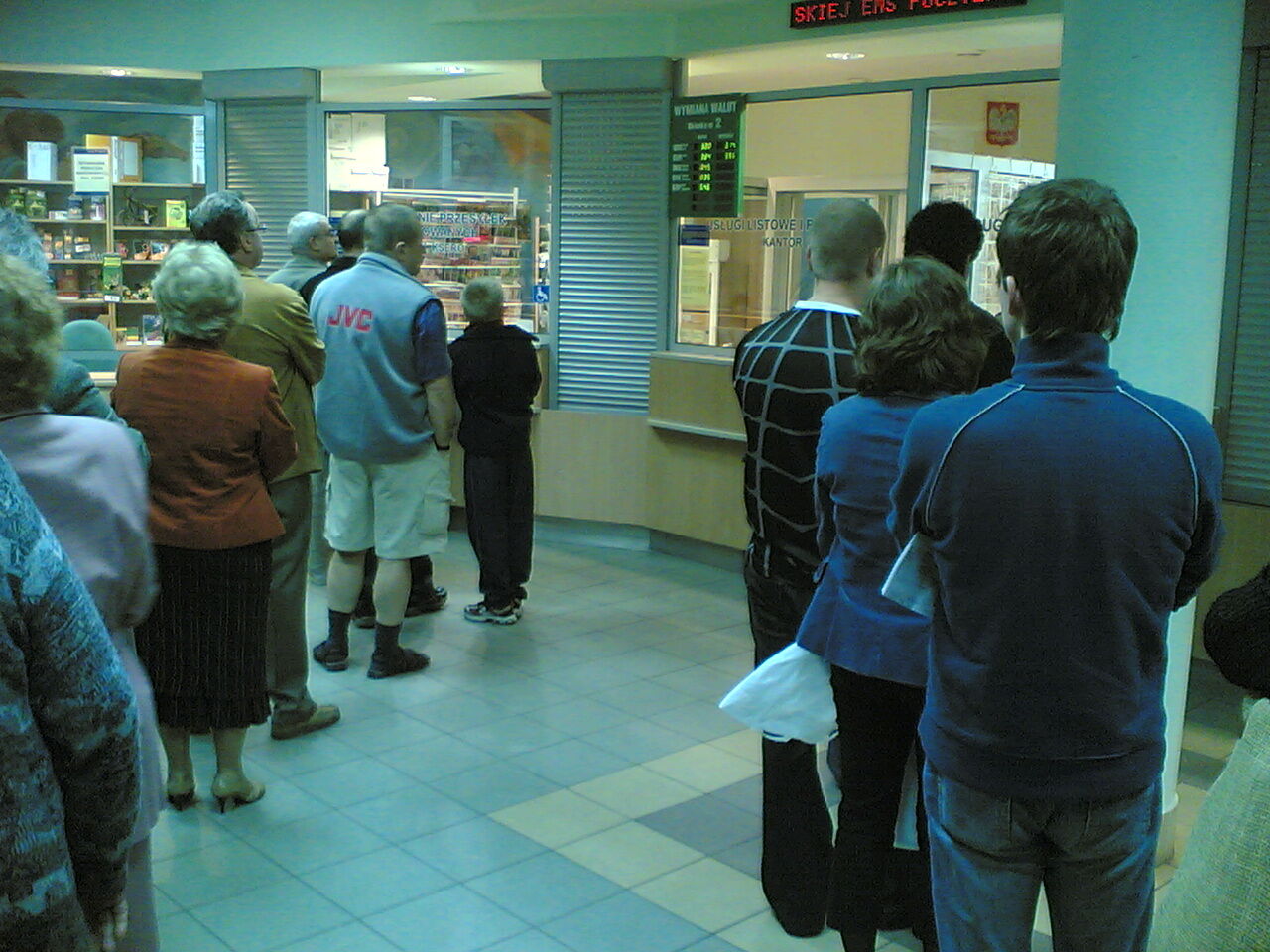 People waiting in a line at a post office counter